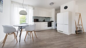 Een moderne keuken met witte kastjes, een eettafel met stoelen en een houten vloer.