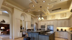 Un'ampia cucina con una grande isola, mobili bianchi e un lampadario.