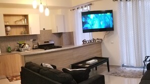Ett modernt vardagsrum med en svart soffa, ett soffbord och en platt-TV som är monterad på väggen.