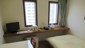 A hotel room with a single bed, a desk with a computer, a coffee maker, and a window with curtains. - Hotel Crown Hills Kitami Annex (Kitami)