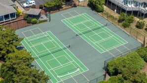 Vista aerea di un complesso di campi da tennis, con numerosi campi immersi nel verde e circondati da edifici residenziali.