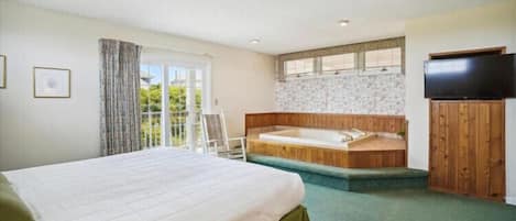Ein Schlafzimmer mit einem großen Bett, einer Holzwanne, einem Fernseher und einem Balkon mit Blick.