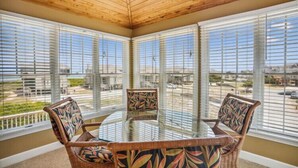 A glass-top table with wicker chairs in a room with large windows.