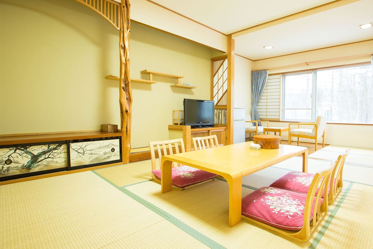 A traditional Japanese-style room with tatami flooring, a low table, and wooden furniture.