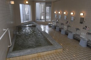 A public bath area with a large soaking tub, multiple showerheads, and tiled walls. - Panorama Inn Yamanakako (Yamanakako)
