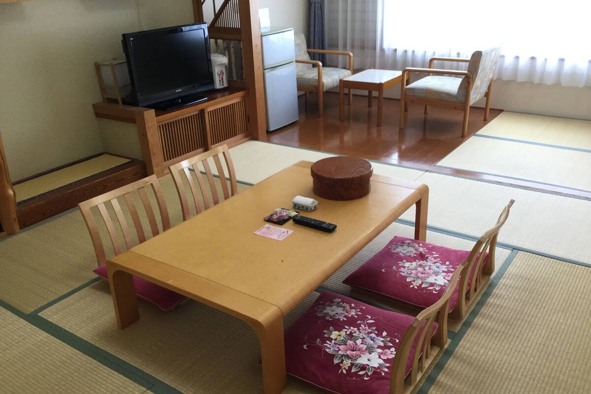 A traditional Japanese-style room with tatami flooring, a low wooden table, and matching chairs.