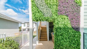 A staircase leading to a second floor, surrounded by a white fence and a green wall with dense foliage. - 2022 Award @ Hosthub, Home Theater/Game Room/Harry Potter Rm Close to Disney (Reunion)