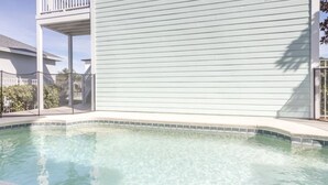 A swimming pool with a tiled edge, a covered patio area, and a light-colored building with a balcony. - 2022 Award @ Hosthub, Home Theater/Game Room/Harry Potter Rm Close to Disney (Reunion)