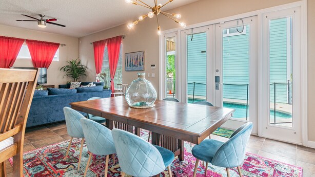 A dining area with a wooden table, blue upholstered chairs, a glass vase centerpiece, and a colorful rug. - 2022 Award @ Hosthub, Home Theater/Game Room/Harry Potter Rm Close to Disney (Reunion)