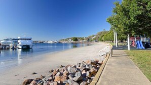 Una platja amb embarcacions amarrades, un parc infantil i un cel serè.
