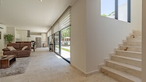 Un amplio salón con sofá, mesa de centro y una escalera que sube a un piso superior.