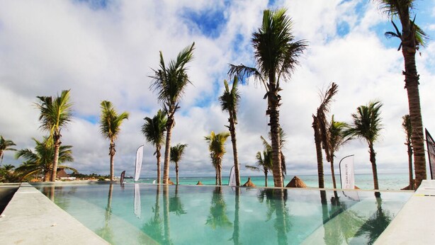 Una piscina cristalina con palmeras y vistas al océano.