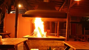 Ein Holz-Sitzbereich im Freien mit einem zentralen Feuerkorb.