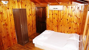 Ein Zimmer mit Holzwänden, einem Bett, einem Kleiderschrank und einer Klimaanlage.