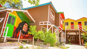 Ein farbenfrohes Haus mit Wandmalerei, einem Balkon und einem kleinen Garten.