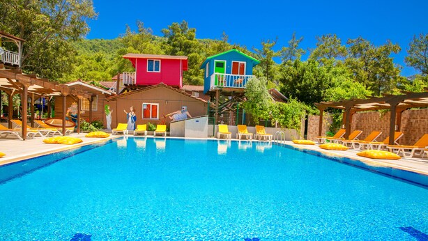 Ein Swimmingpool mit Liegestühlen und farbenfrohen Gebäuden im Hintergrund.