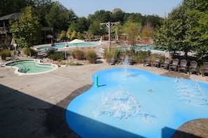 Une piscine agrémentée d’une fontaine, entourée de chaises longues, avec un bâtiment en arrière-plan.