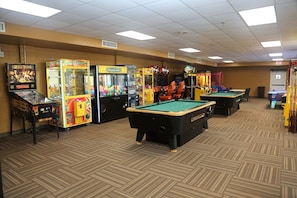Une salle de loisirs équipée de tables de billard, de jeux d’arcade et d’un espace dédié au jeu de billard.