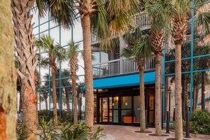 Enter a tranquil oasis amidst the city, surrounded by lush palm trees and a striking grid-patterned facade.