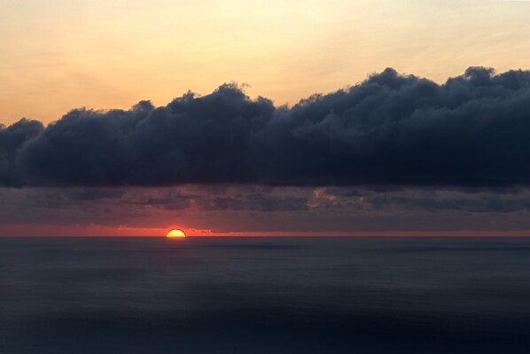 Ein Sonnenuntergang über einem Gewässer mit Wolken.