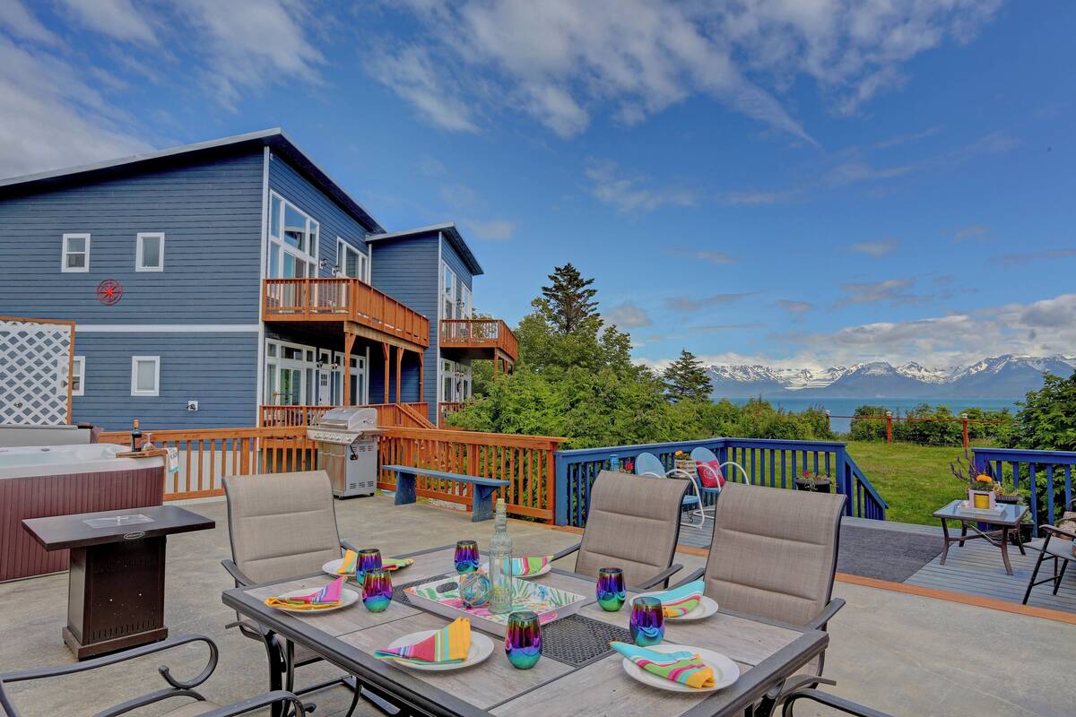 A deck with outdoor seating, a hot tub, and a view of mountains.