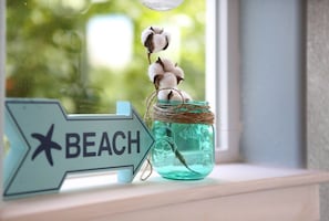 Um letreiro com a palavra 'BEACH' e uma estrela, ao lado de um pote com algodão e barbante.