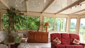 Ein geräumiges Wohnzimmer mit Essbereich, großen Fenstern und einer Zimmerpflanze.
