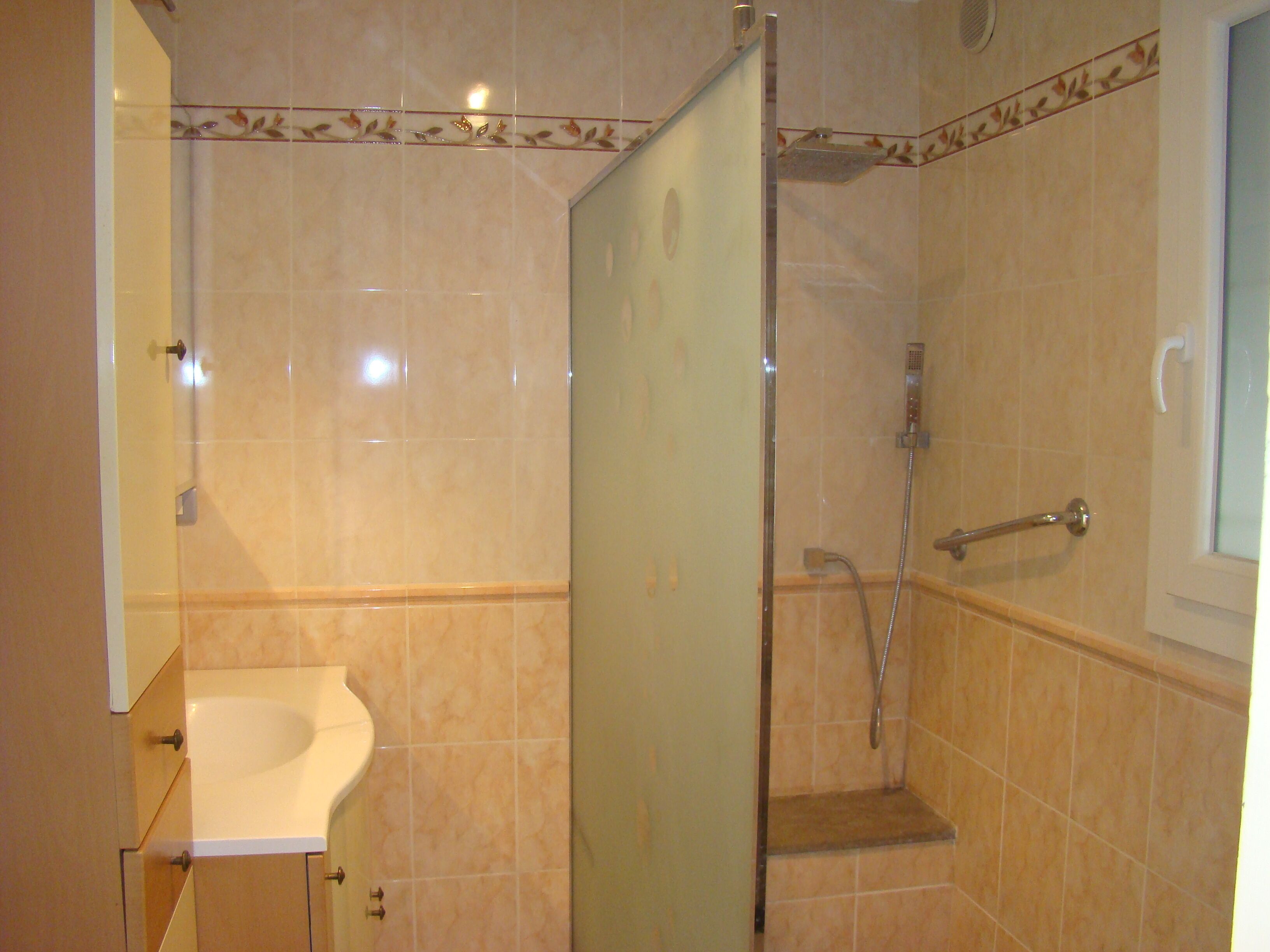 A bathroom with a glass-enclosed shower, a sink, and a toilet.