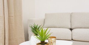 A modern living room with a white sofa, a small white table, and two decorative pots on the table.