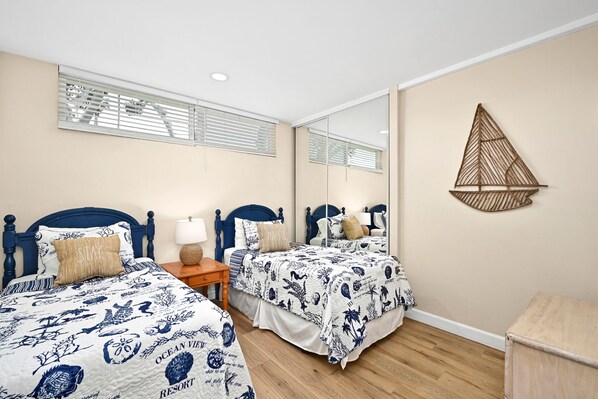 A bedroom with two beds, a mirror, and a wall-mounted decorative piece.