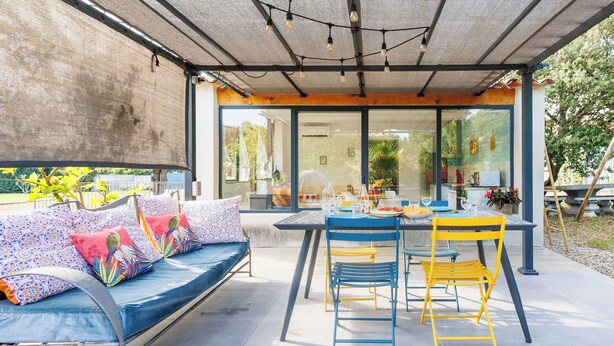 Un espacio de estar techado al aire libre con un sofá, sillas y una mesa.