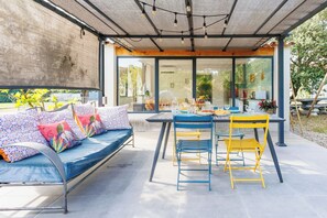 A covered outdoor seating area with a sofa, chairs, and a table.