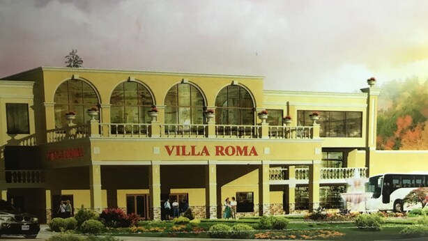A hotel named Villa Roma with a yellow facade, arched windows, and a balcony.