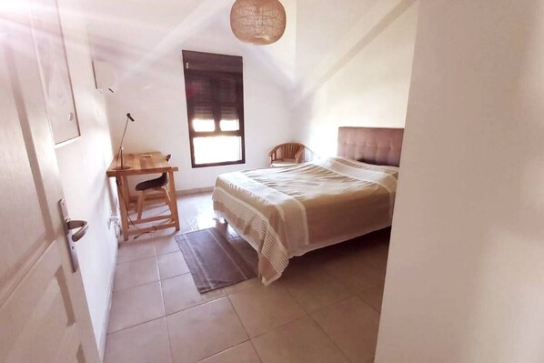 A bedroom with a bed, a desk, a chair, and a window. - Apartment "Sweethome" Furnished accommodation *** sea view in Saint-Leu center (Saint-Leu)