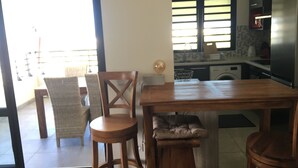 Eine Küche mit Holztisch und Stühlen, einem Kühlschrank und einem Fenster mit Jalousien.
