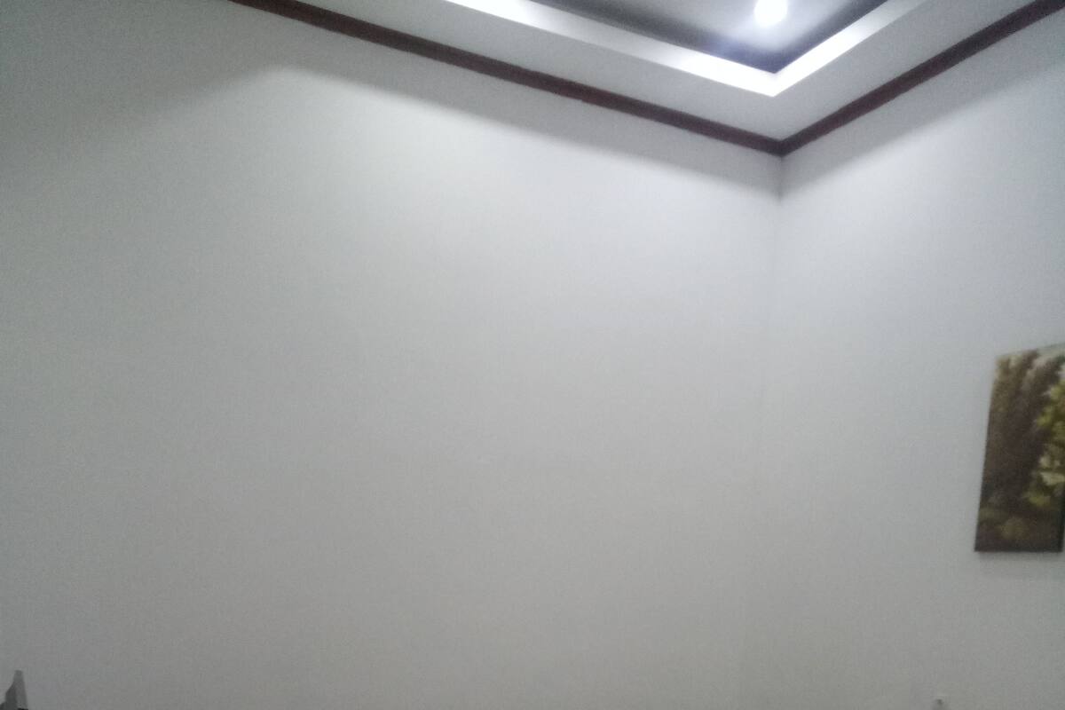 A bedroom with a wooden desk, a bed, and a ceiling light.