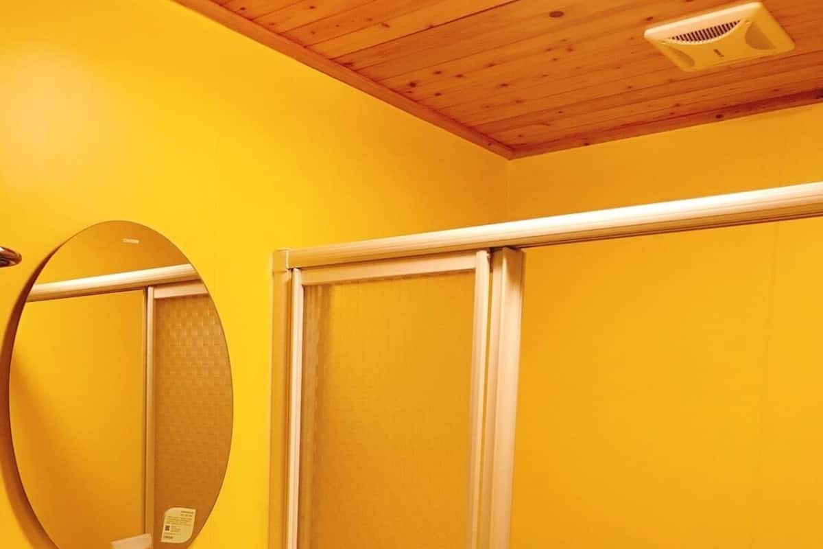 A bathroom with a white sink, a round mirror, and a glass shower enclosure.