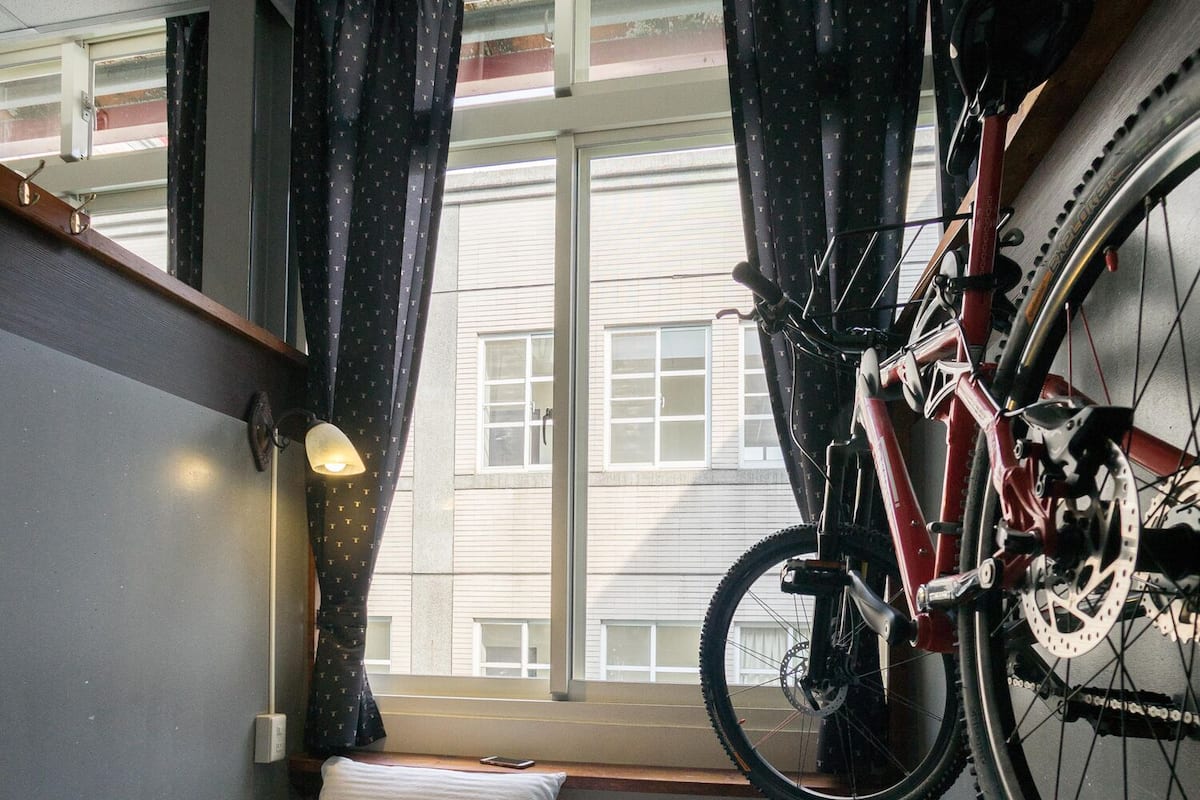 A compact room with a bed, a laptop, and a bicycle mounted on the wall.