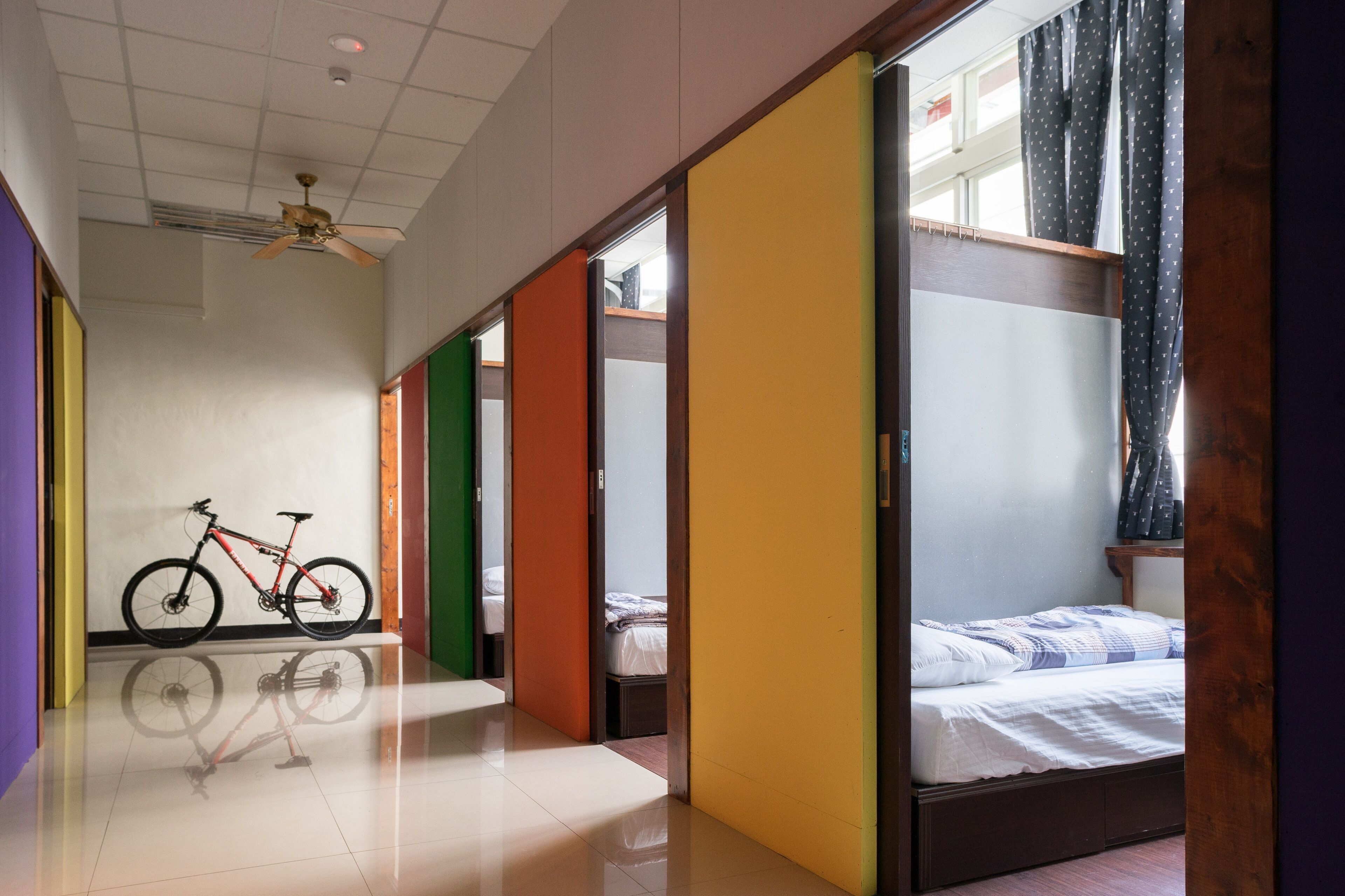 A hotel room with a bed, a bicycle, and a view of the street.