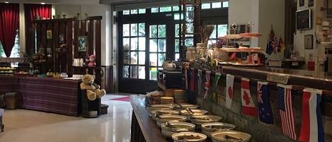 A restaurant with a long counter, multiple flags, and a variety of dishes displayed.