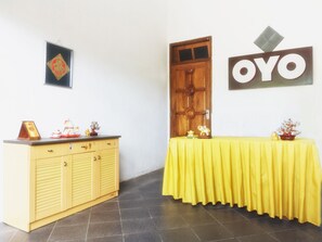 A room with a yellow table, a wooden door, and a wall-mounted sign. - OYO 801 Hansa Homestay (Pacitan)