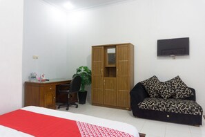 A bedroom with a bed, a desk, a wardrobe, a TV, and a sofa. - OYO 801 Hansa Homestay (Pacitan)