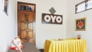 A room with a wooden door, a table with a yellow tablecloth, and a wall-mounted sign that reads "OYO".