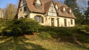 A traditional half-timbered house with a steeply pitched roof, multiple chimneys, and a stone foundation. - Family house in the middle of a green (Le Mont-Saint-Adrien)