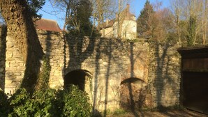 A stone structure with two arched openings, surrounded by greenery and trees. - Family house in the middle of a green (Le Mont-Saint-Adrien)