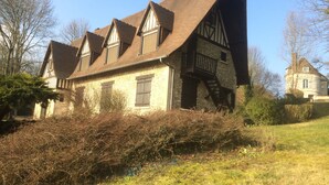 A traditional half-timbered house with a steeply pitched roof, stone walls, and a wooden staircase leading to a balcony. - Family house in the middle of a green (Le Mont-Saint-Adrien)