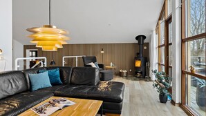 En moderne stue med en sort lædersofa, et træbord og et stort vindue.