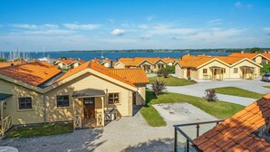 En række gule huse med orange tage, pænt arrangeret med en grussti imellem, med udsigt over et vandareal.
