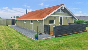 A single-story building with a red-tiled roof, a small porch, and a black fence. - 3 bedroom amazing home in Haderslev (Haderslev)