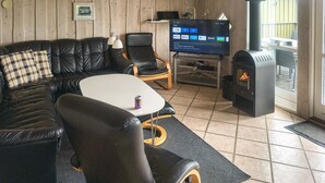 A cozy living room with a leather sofa, a TV, a fireplace, and a wooden wall. - 3 bedroom amazing home in Haderslev (Haderslev)